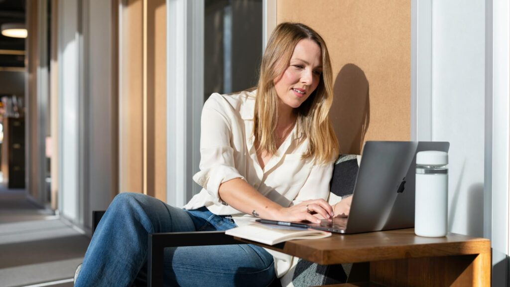 Eine engagierte Geschäftsfrau arbeitet an ihrem Laptop in einem sonnendurchfluteten Büro.